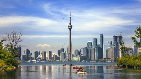 landscape of a city with backdrop of skyscrappers in front of river with people kayaking on it