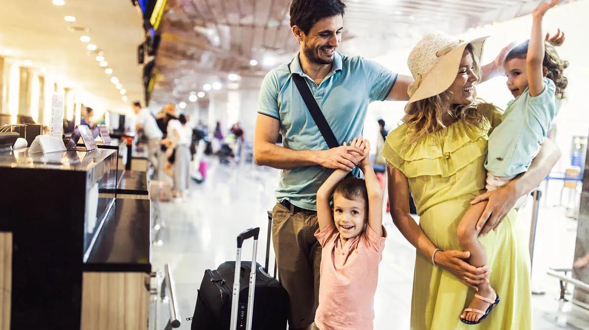 family of parents with young daughter and son at the airport very excited