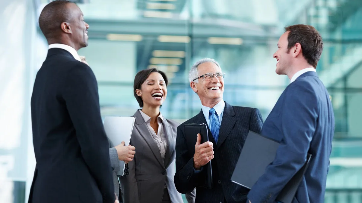 three man and a woman in suits standing in office foyer laughing