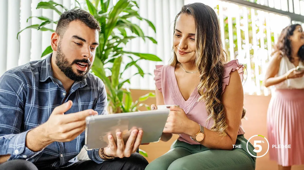 man and woman sitting down looking at a tablet discussing work