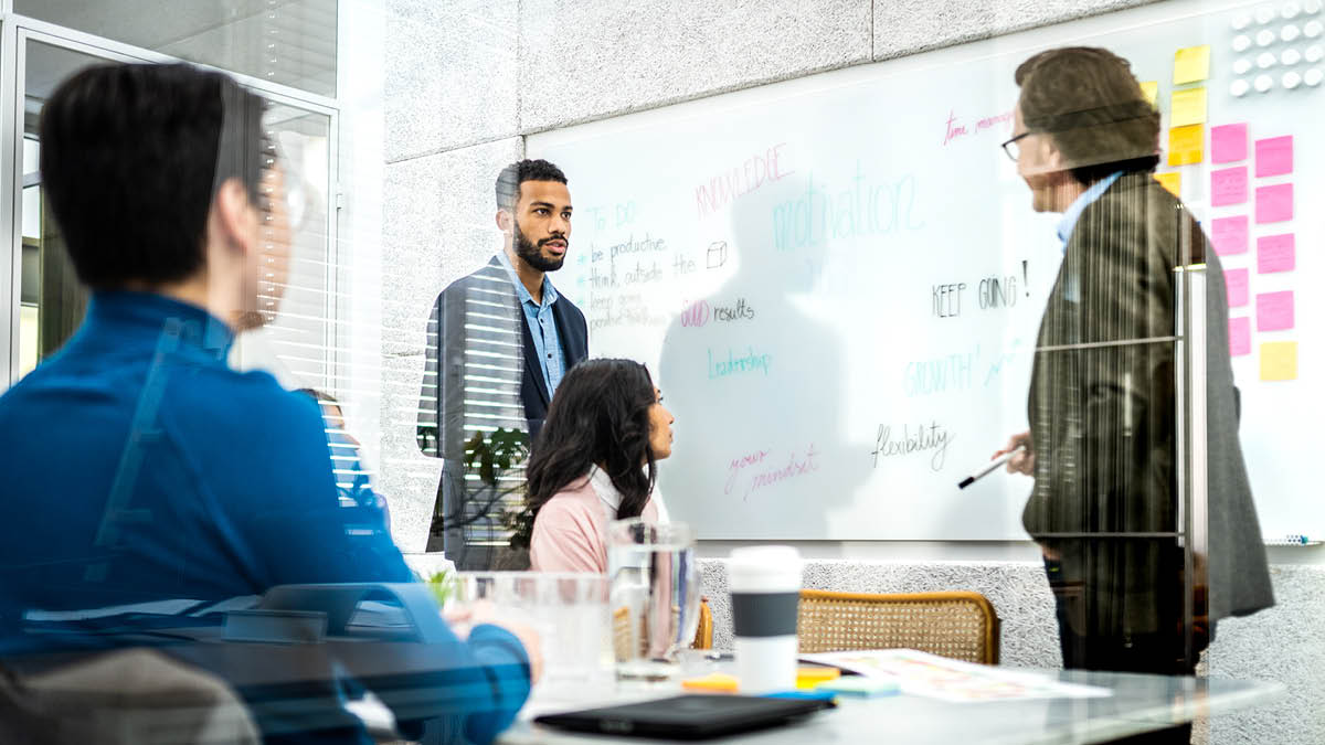 Colleagues in an office looking at a white board