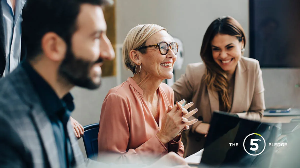 Group of colleagues smiling and chatting at a desk, showing signs of positive mental health