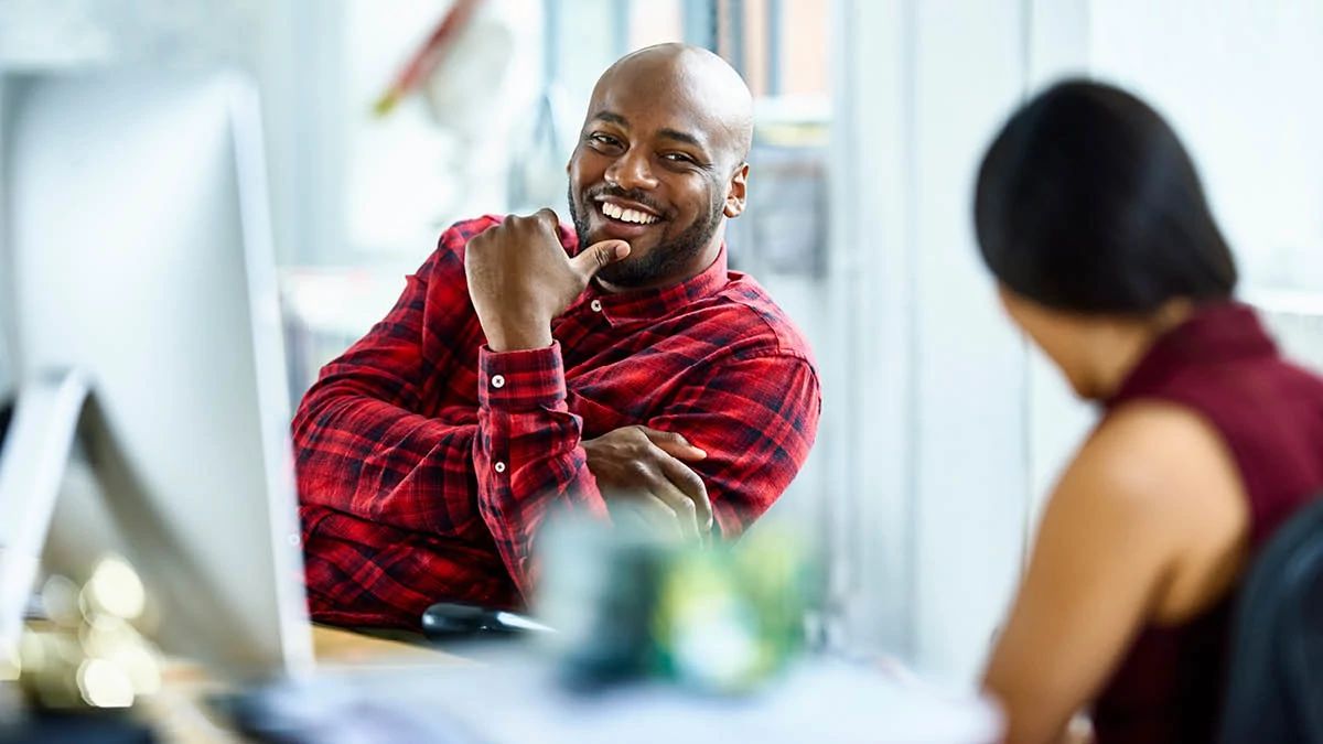 Two young workers in an office looking happy