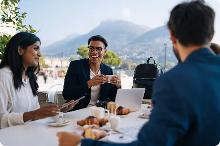 Group of young colleagues having an al fresco breakfast meeting with beautiful mountains in the background.