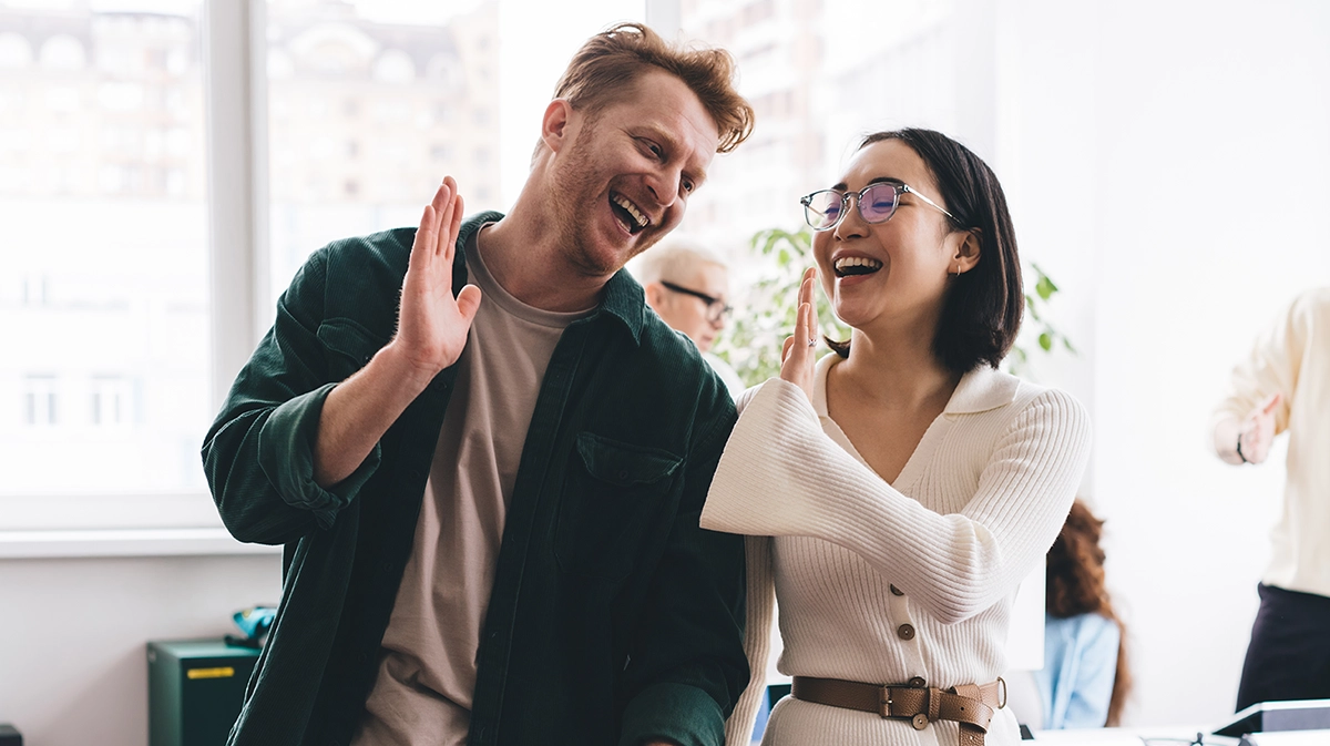 Couple of colleagues high fiving and smiling