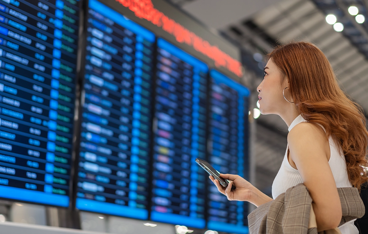 young asian woman reviewing airport departure board