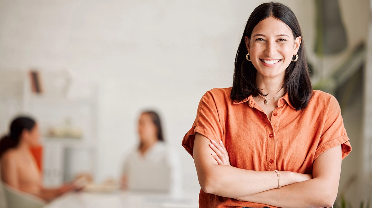 Smiling woman wearing an orange top with a blurred background