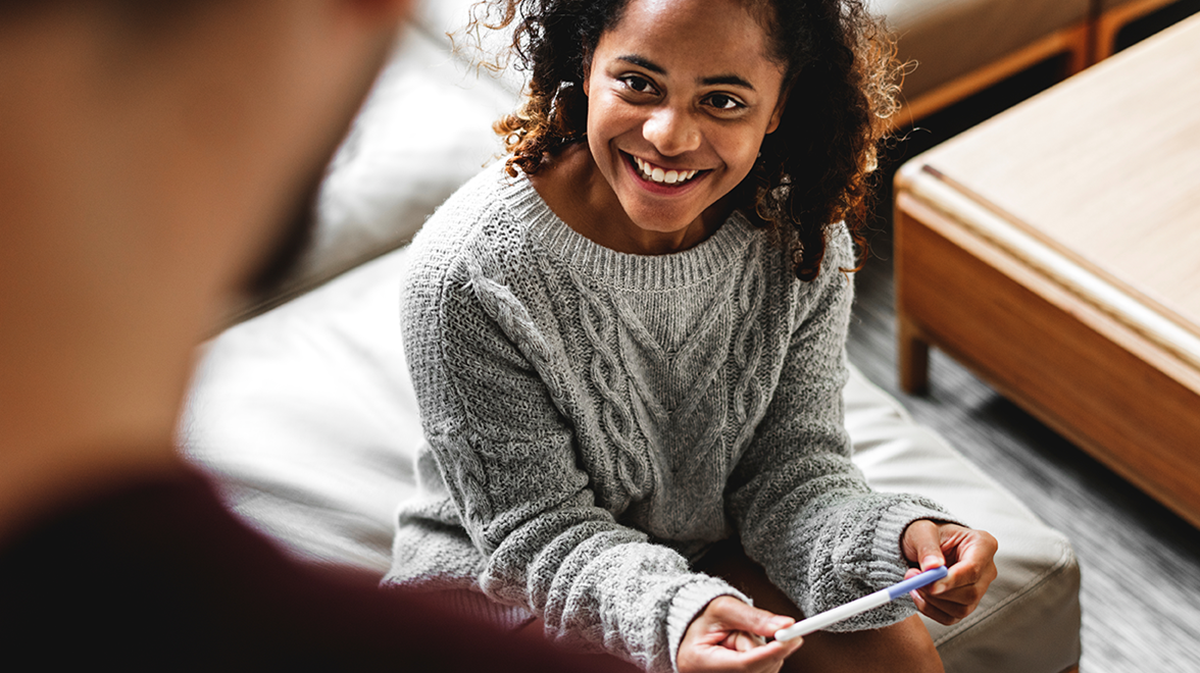 Smiling woman holding pregnancy test
