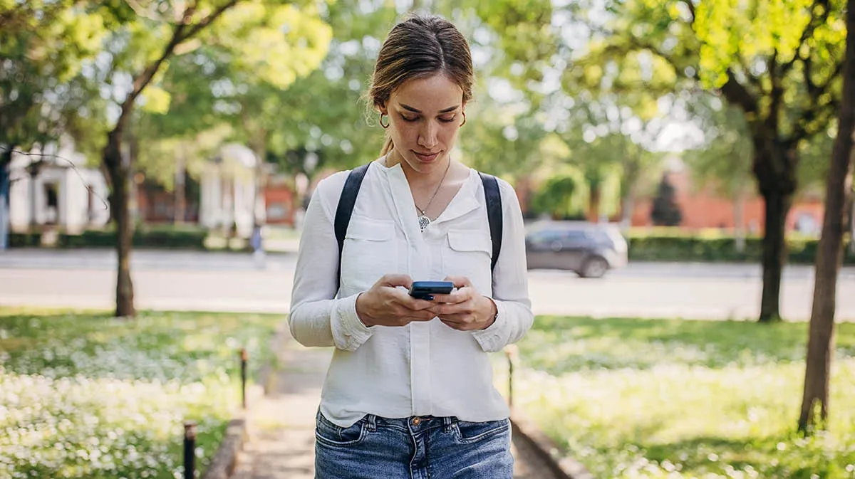 Student walking outside on a mobile phone looking up medical diagnosis