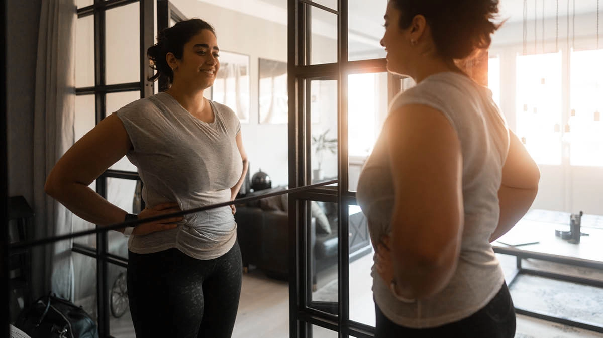 A young woman looking at her reflection in the mirror, smiling