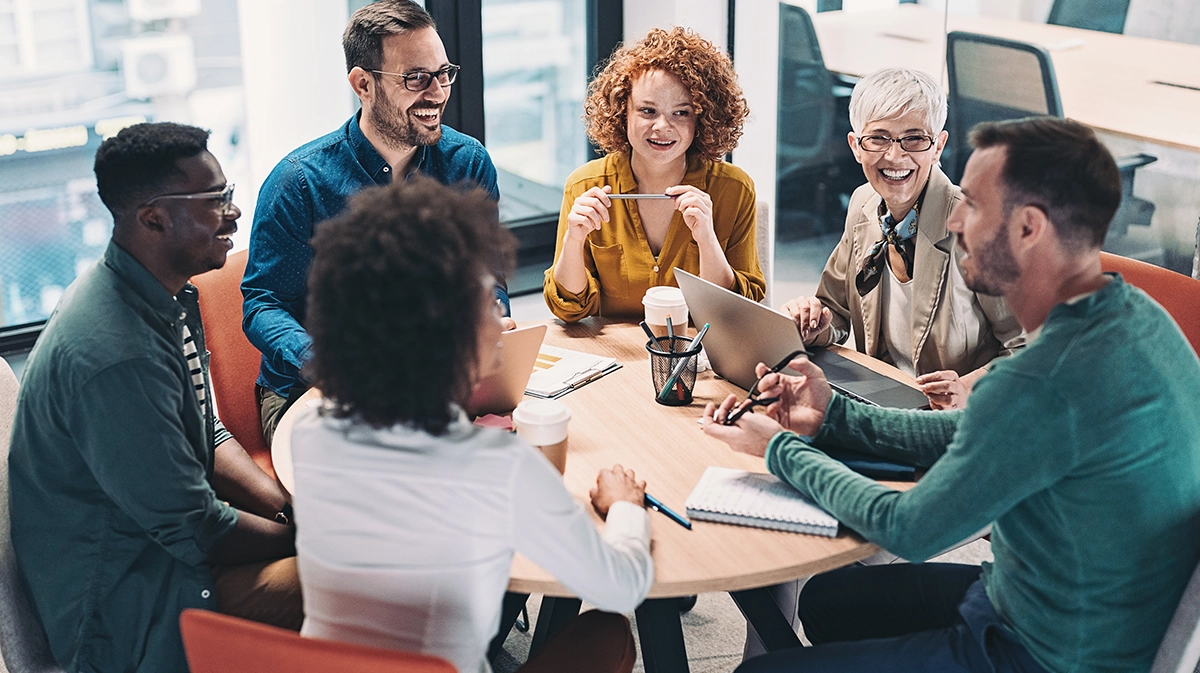 Mixed Group Of Business People Sitting Around A Table And Talking