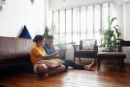 young couple sitting on the floor looking at a laptop