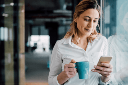 working woman having a coffee and looking at her phone