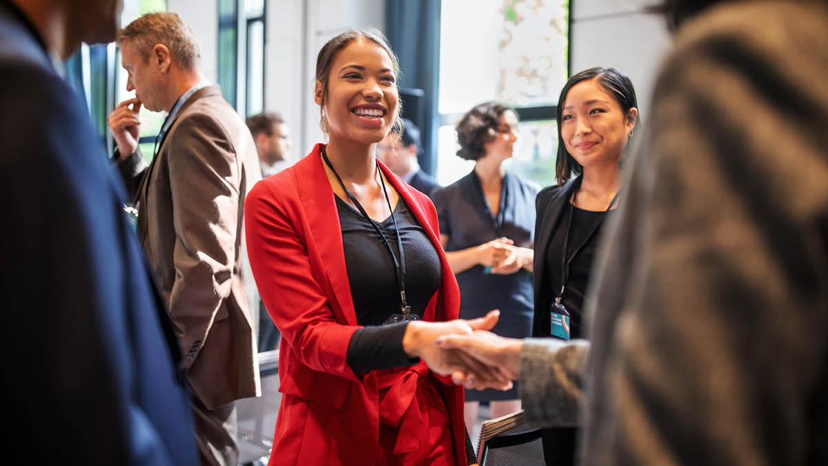 Smiling woman greeting another person with a traditional handshake