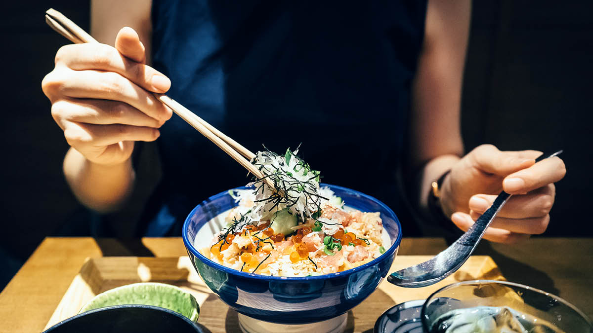 Chopsticks being used correctly to eat a bowl of rice and vegetables