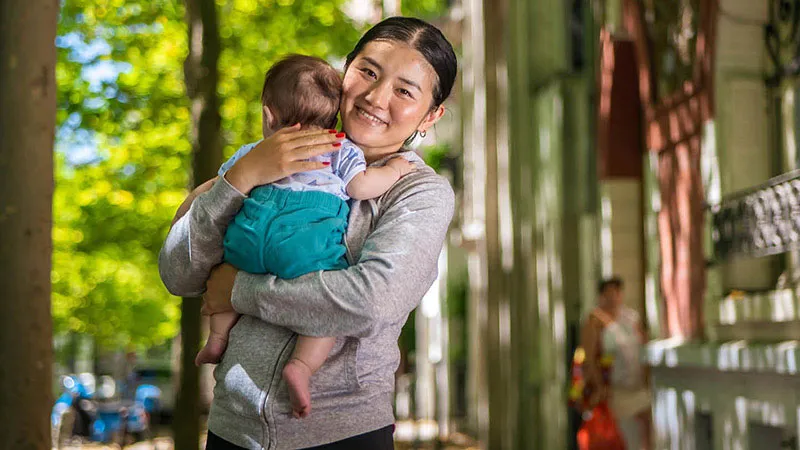 Chinese woman smiling holding baby in a quiet street