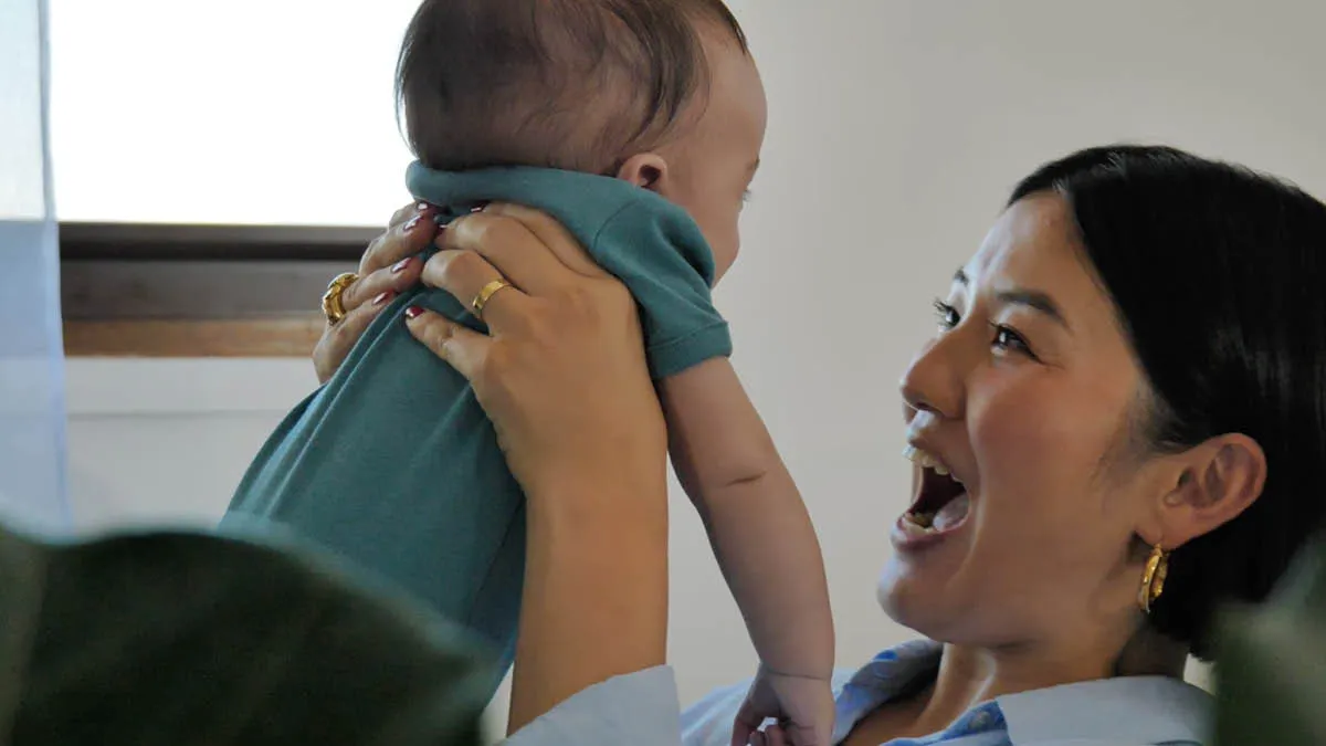 Japanese expat Akiko lifting up her baby son while smiling
