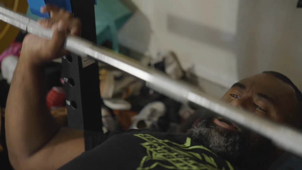 Fijian expat Pate lying on his back lifting weights in a gym