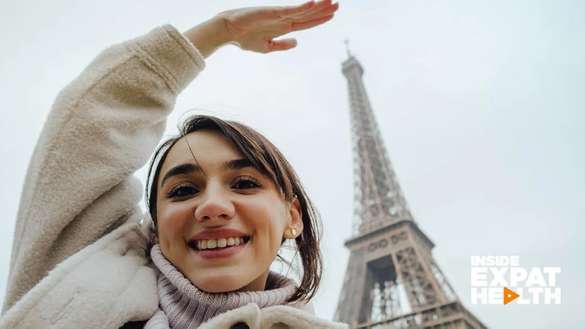 Young, smiling woman standing in front of the Eiffel Tower, France.