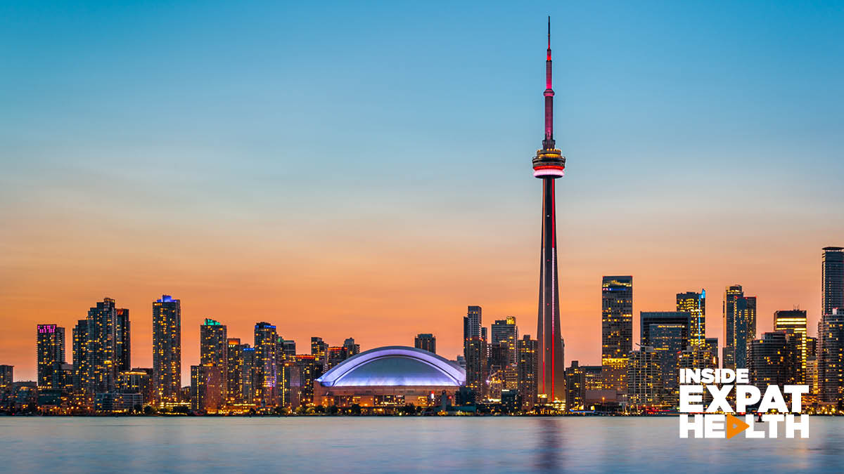 A sunset view of a Canadian skyline, with skyscrapers lit up in neon