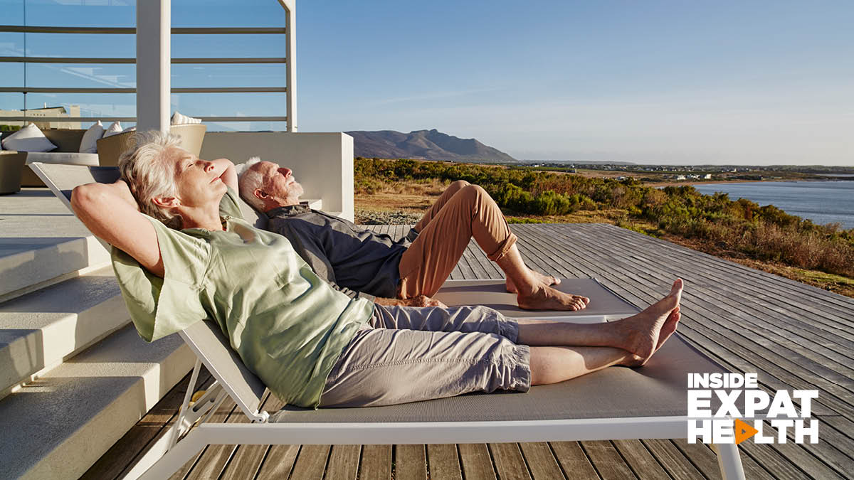 A retired couple lying on sun loungers looking out to the water