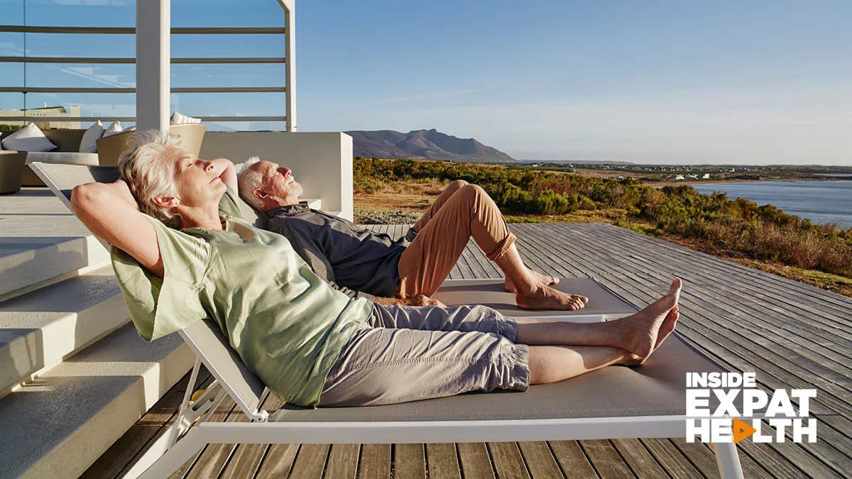 A retired couple lying on sun loungers looking out to the water