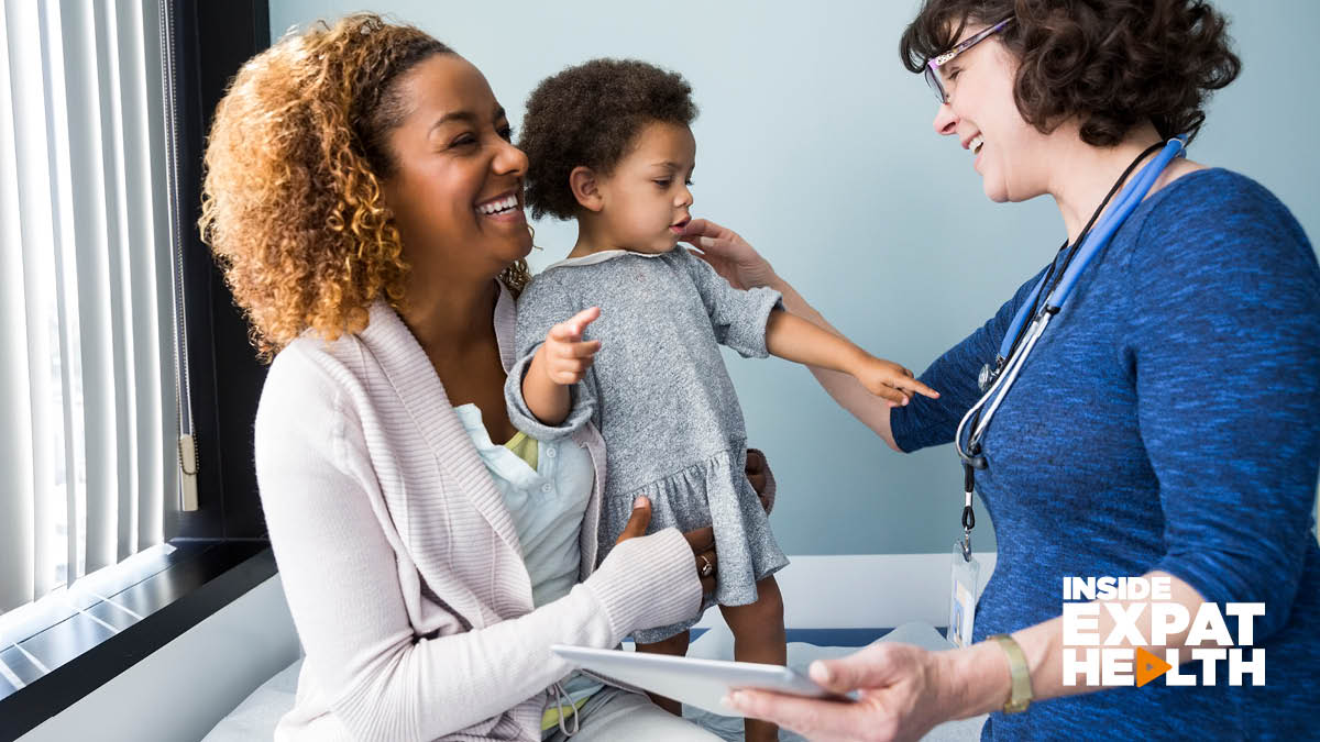 A happy mother and young child visiting the doctor. The child is pointing at the doctor