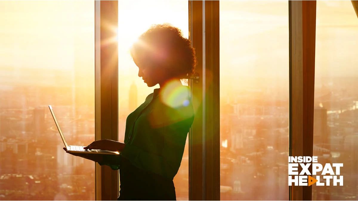 woman standing by the window, looking at her laptop