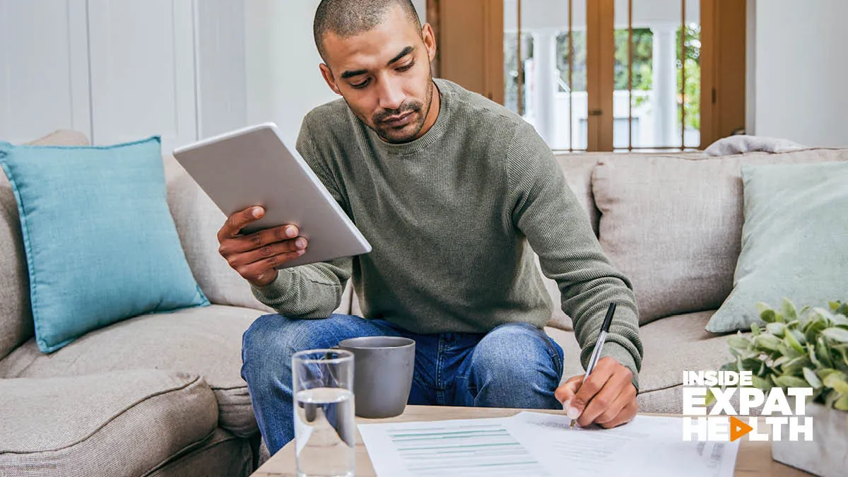 A man sitting on a couch with a notebook  in one hand and writing with the other hand