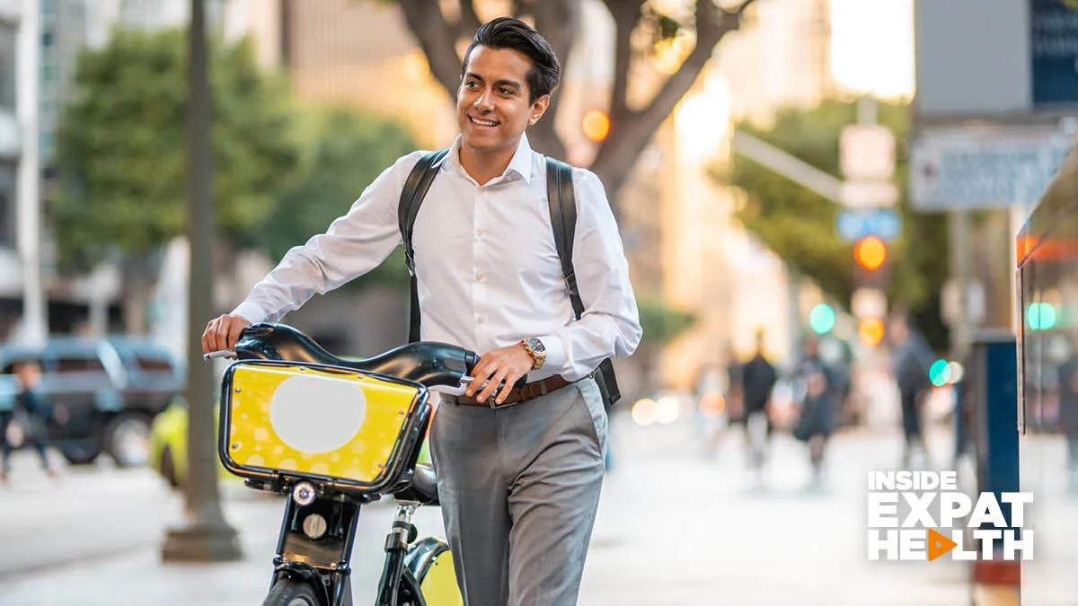 young man in the street looking happy, holding his bike