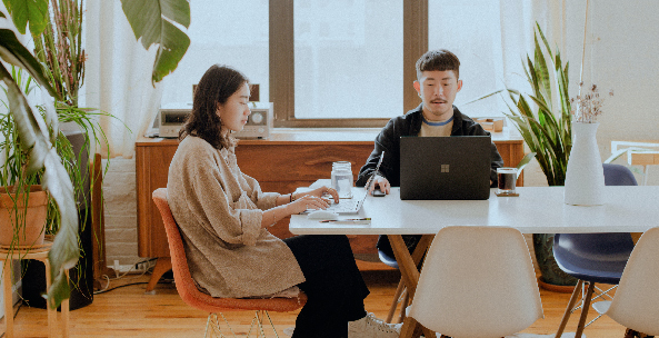 A young professional couple sits at their dining room table quietly working from home together.